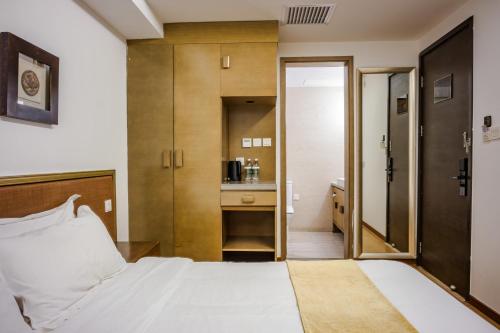 a bedroom with a white bed and a kitchen at Beijing Shichahai Shadow Art Performance Courtyard in Beijing