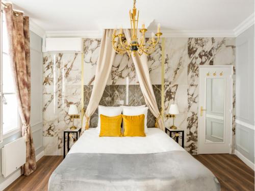 - une chambre avec un lit doté d'oreillers jaunes et d'un lustre dans l'établissement Merveil - Luxury Suite - Marais - Antoine II, à Paris
