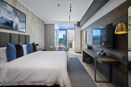 a bedroom with a large bed and a television at The Capital Pearls Hotel in Durban