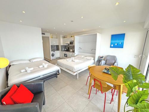 - une chambre avec 2 lits, une table et une salle à manger dans l'établissement PROMENADE HOLIDAY - ROYAL LUXEMBOURG PROMENADE, à Nice