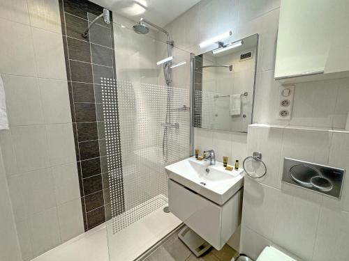 une salle de bain blanche avec une douche et un lavabo dans l'établissement PROMENADE HOLIDAY - ROYAL LUXEMBOURG PROMENADE, à Nice