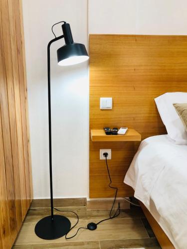 a black floor lamp in a bedroom with a bed at AMU- Apartamentos Mistérios da Urzelina in Urzelina