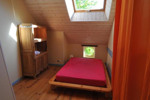 - une petite chambre mansardée avec un lit rouge dans l'établissement gîte ERZIWEZH, à Sainte-Marie