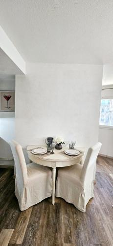 a dining room table with white chairs and a white wall at Canebière Charm in Marseille