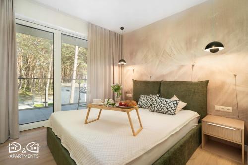 a bedroom with a bed with a table on it at Apartament Zielony D&D APARTMENTS in Międzywodzie
