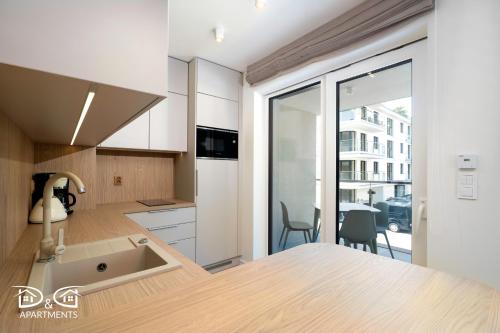 a kitchen with white cabinets and a sink at Apartament Zielony D&D APARTMENTS in Międzywodzie