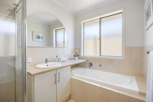 a bathroom with a tub and a sink and a mirror at Halcyon Haven in Aldinga Beach