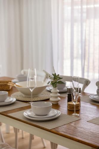 a wooden table with plates and wine glasses on it at Halcyon Haven in Aldinga Beach