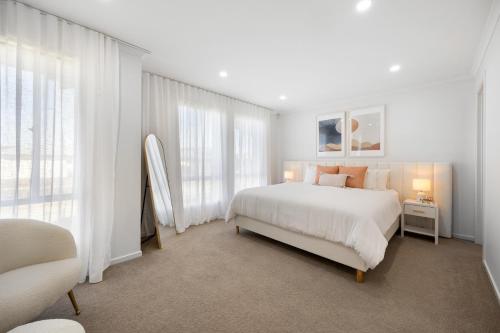 a white bedroom with a large bed and windows at Halcyon Haven in Aldinga Beach