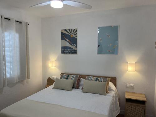 a white bedroom with a bed with two pillows at Castellsol 203 by SOM Menorca in Arenal d'en Castell