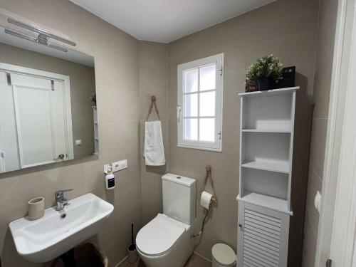 a bathroom with a toilet and a sink and a mirror at Castellsol 203 by SOM Menorca in Arenal d'en Castell