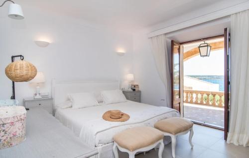 a white bedroom with a bed and a balcony at Villa Cabrera in Colonia Sant Jordi