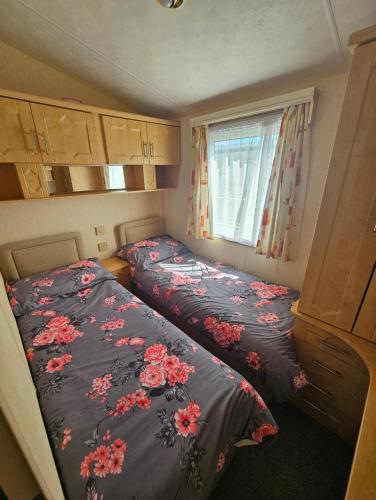 a small bedroom with two beds and a window at Meadow Lakes 56 in Chapel Saint Leonards