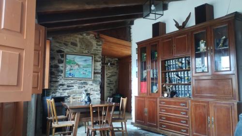 a dining room with a table and a stone wall at Granja del Peregrino in O Pino 