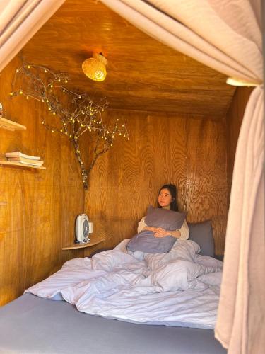 a woman laying in a bed in a room at Cú Trên Cây Homestay in Xuan An