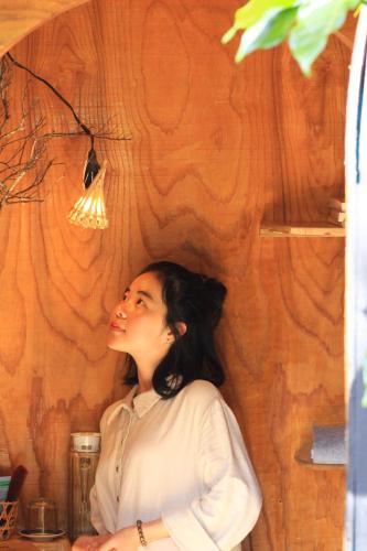 a woman standing in a room with a wall at Cú Trên Cây Homestay in Xuan An