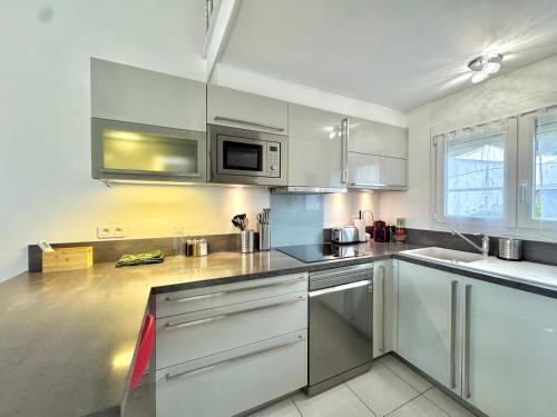 une cuisine avec des armoires blanches et des appareils en acier inoxydable dans l'établissement Maison de la pinède, au Cap d'Agde