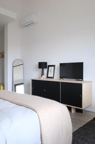 a bedroom with a bed and a dresser with a television at The Black Sheep BnB in Arbus