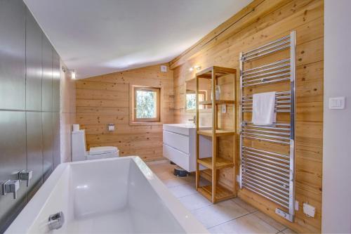La salle de bains est pourvue d'une baignoire blanche et d'un mur en bois. dans l'établissement Chalet la Ficle, à Saint-Jean-dʼAulps