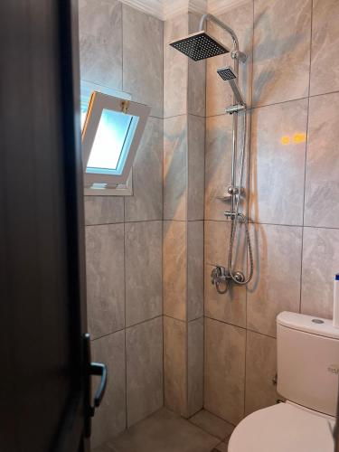 a bathroom with a shower with a toilet and a window at Kılavuz otel in Bodrum City