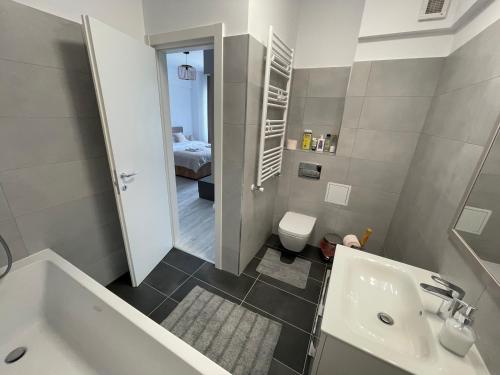 a bathroom with a tub and a sink and a bedroom at Unirea Towers Deluxe Apartment Modern & Chic in Iaşi