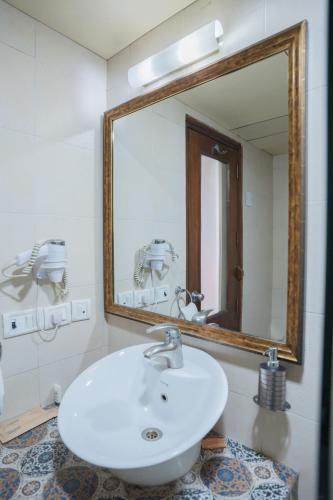 a bathroom with a white sink and a large mirror at Ahuja Residency Parklane in Gurgaon