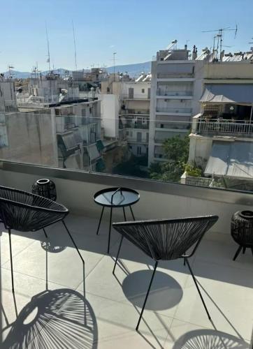a balcony with three chairs and a view of a city at Luxury Maisonette with Shared Pool in Athens