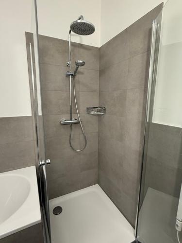 eine Dusche mit Glastür neben einem Waschbecken in der Unterkunft ElbeCity Apartment in Dresden