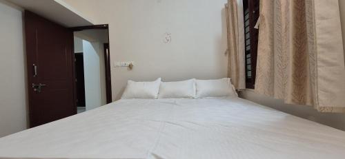 a large white bed in a room with a window at Chiraanya Service Apartment in Chikmagalūr