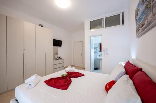 een wit bed met rode kussens erop bij Vila Basho in Sarandë