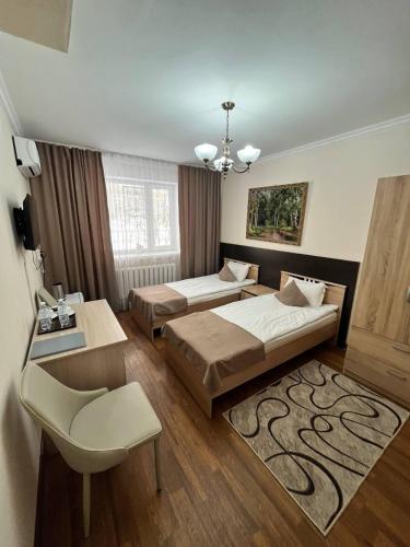 a bedroom with two beds and a table and a chair at Skif Hotel in Astana