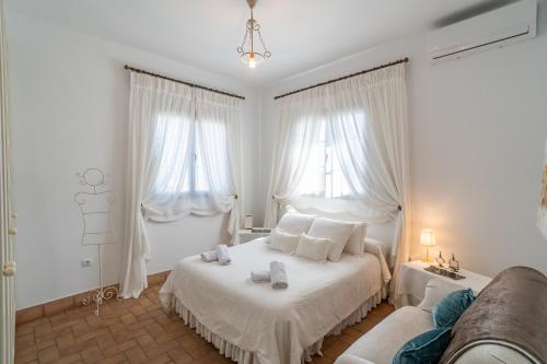 a white bedroom with a bed and a couch at Casa rural Pozo Viejo in Marchena