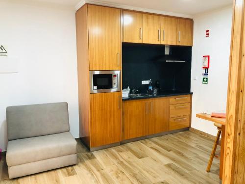a small kitchen with a chair and a microwave at AMU- Apartamentos Mistérios da Urzelina in Urzelina