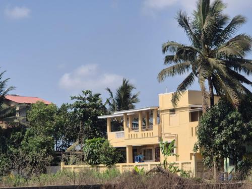 a yellow house with a palm tree in front of it at Prashant Homestay & Villa, Alibag in Alibaug