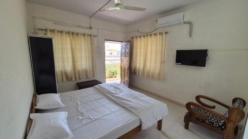 a bedroom with a bed and a tv and a window at Prashant Homestay & Villa, Alibag in Alibaug