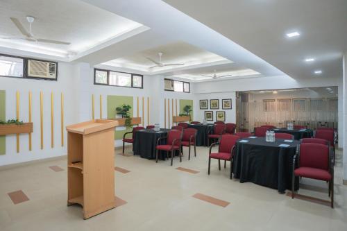 a conference room with tables and red chairs and a podium at Ahuja Residency Parklane in Gurgaon