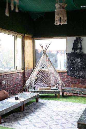 a hammock in a room with two benches and windows at The tented tribe in Dharamshala