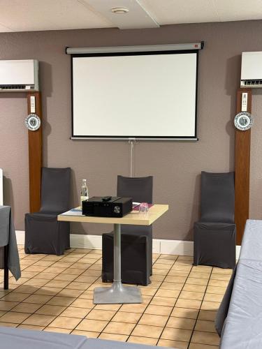 a room with a table with chairs and a white screen at Brit Hotel Besancon l'Horloge in Besançon