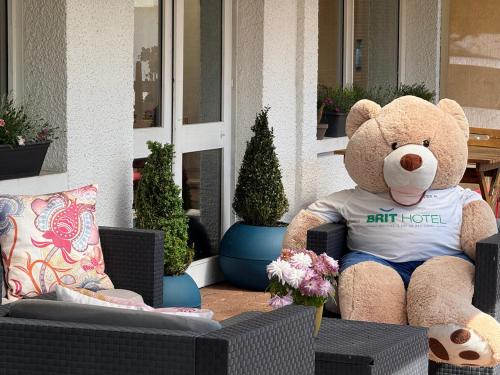 a large teddy bear sitting in a chair on a porch at Brit Hotel Besancon l'Horloge in Besançon