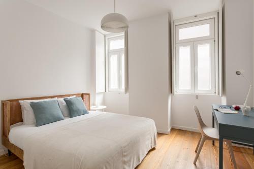 a white bedroom with a bed and a desk at Calçada de Santo Amaro Apartments in Lisbon