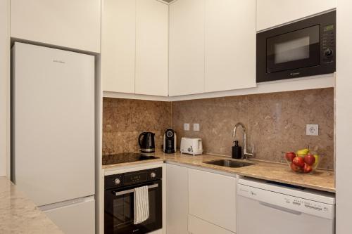 a kitchen with white cabinets and a sink and a microwave at Calçada de Santo Amaro Apartments in Lisbon
