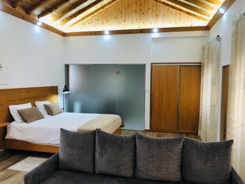a bedroom with a bed and a couch at AMU- Apartamentos Mistérios da Urzelina in Urzelina