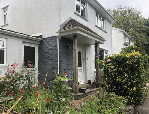 a white house with a white door and some flowers at Stylish Room Close to Beaches in Falmouth