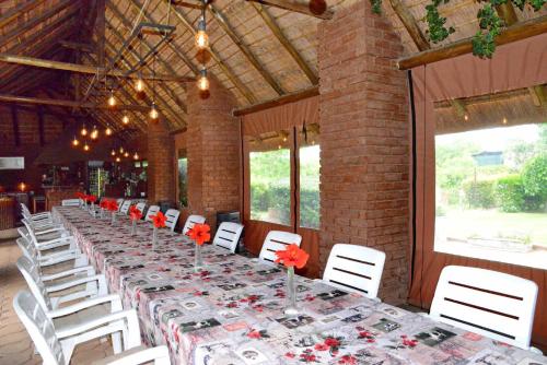 a long table with white chairs and red flowers on it at Owls Loft Guest House in Midrand