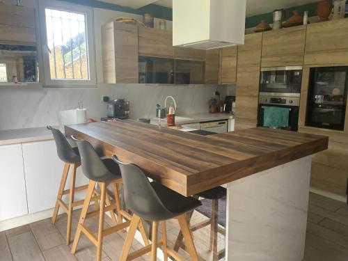 une cuisine avec un grand comptoir en bois entouré de chaises dans l'établissement Maison laurier, à Saint-Just