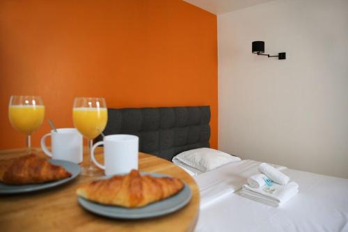 - une table avec deux verres de jus d'orange et des croissants dans l'établissement 302 sejournez dans un studio de charme paris 5, à Paris
