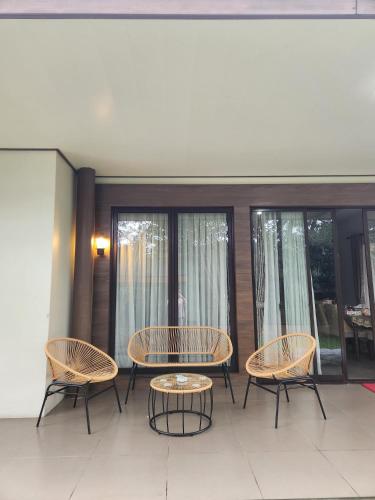 a patio with a table and chairs and windows at Five Leo’s villa in Gadok 1