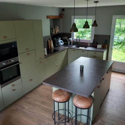 - une cuisine avec une table et des tabourets dans l'établissement Maison de charme à la campagne, à Juvardeil