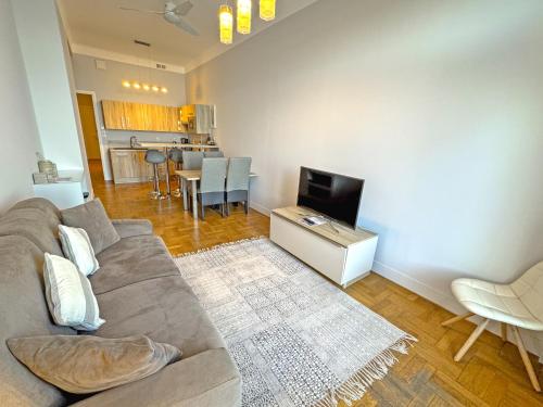 un salon avec un canapé et une télévision dans l'établissement PROMENADE HOLIDAY - ROCAMARE PROMENADE, à Nice