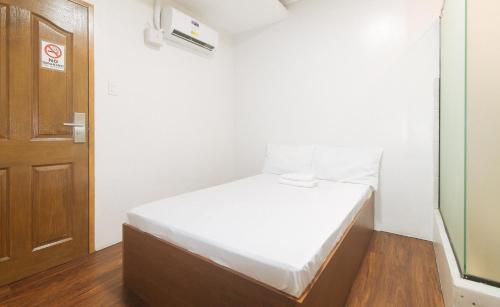 a small room with a bed and a door at GREN PLACE near Baclaran Airport Road by RedDoorz in Manila